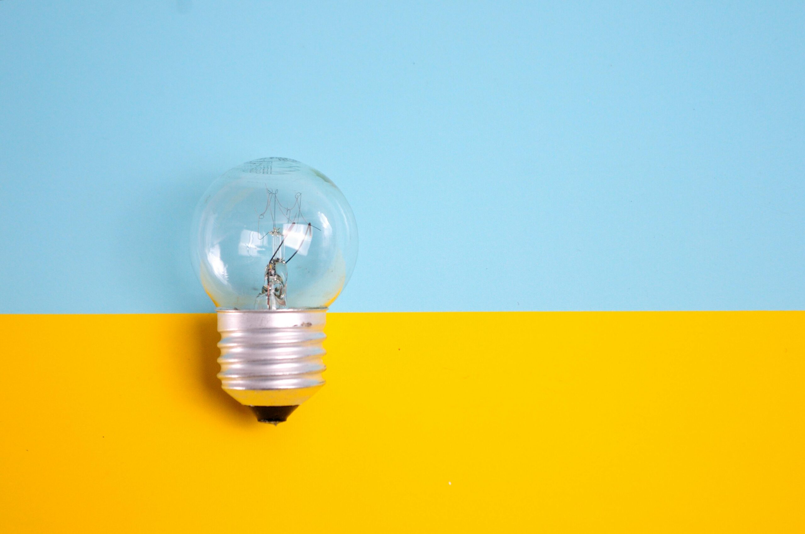 Lightbulb resting on a yellow and blue background for Twenty-Two's website disclaimer
